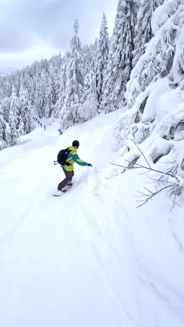 Man snowboarder rijden door besneeuwde helling in prachtige bergen — Stockvideo