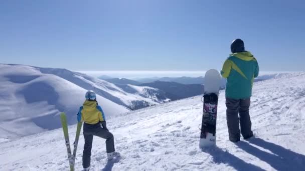 Couple skieur et snowboarder regardant une vue incroyable sur les montagnes enneigées — Video