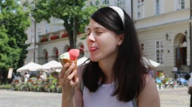 Sıcak bir günde dondurma yiyen gülümseyen kadın.