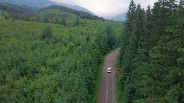 Widok z lotu ptaka SUV samochód poruszający się drogą w górach zachmurzenie mgliste deszczowa pogoda — Wideo stockowe