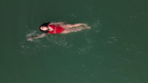 Sorrindo mulher bonita em maiô vermelho nadando de volta na água — Vídeo de Stock