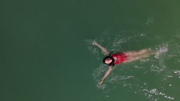 Sorrindo mulher bonita em maiô vermelho nadando de volta na água — Vídeo de Stock