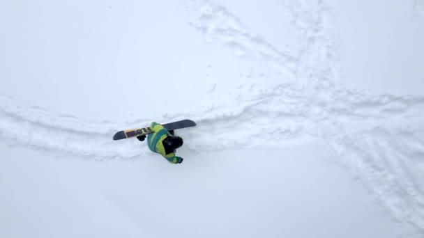 Człowiek wspinaczka przez snowed wzgórzu z snowboardem — Wideo stockowe