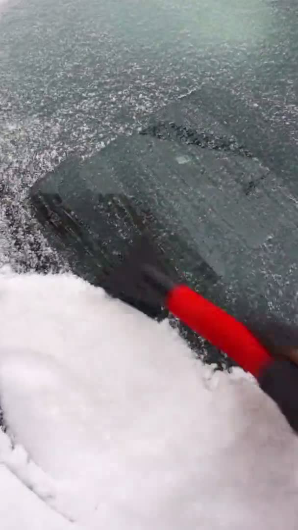 Het reinigen van de voorruit van een auto van ijs met scrapper — Stockvideo