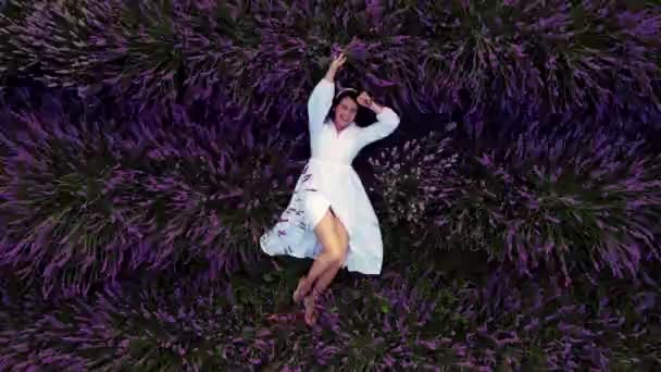 Prachtige vrouw in witte jurk liggen in lavendel veld — Stockvideo
