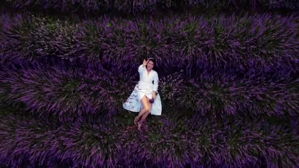 Vacker kvinna i vit klänning ligger ner i lavendel fält — Stockvideo