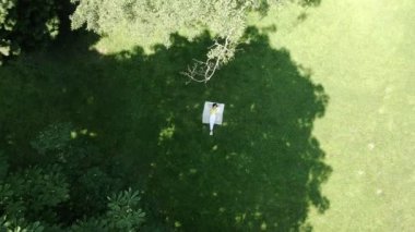 gülümseyen kadın yeşil çimlerin üzerinde battaniyeye uzandı.