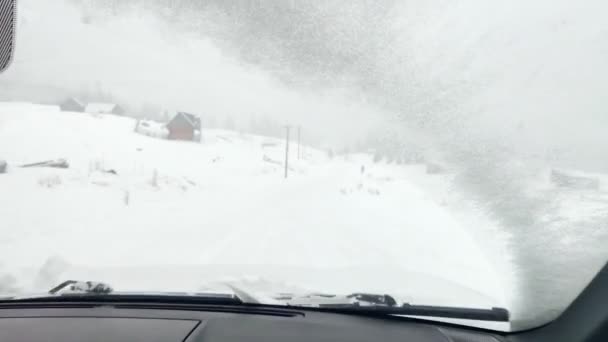 Auto durch verschneite Bergstraße gefahren — Stockvideo