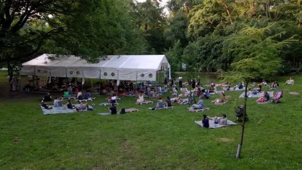 Lviv, Ucrania - 19 de julio de 2021: personas tumbadas en el suelo en el parque público escuchando música — Vídeos de Stock