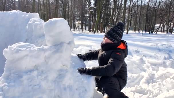 Niño construyendo fortaleza de nieve — Vídeos de Stock