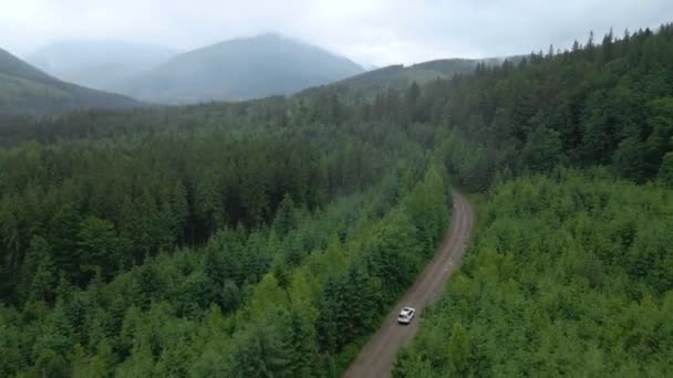 Vista aérea del coche suv que se mueve por camino camino en las montañas nubladas nublado tiempo lluvioso — Vídeo de stock