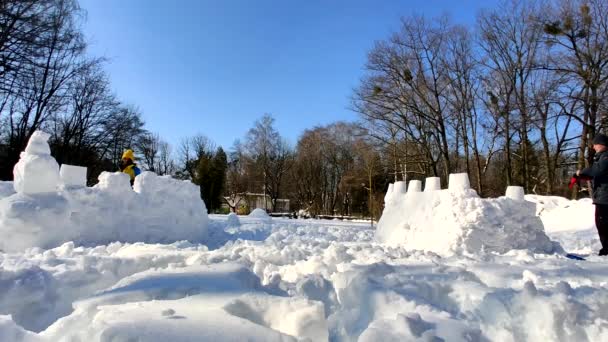 Ojciec i syn bawią się śnieżkami ukrywając się w śnieżnej fortecy — Wideo stockowe