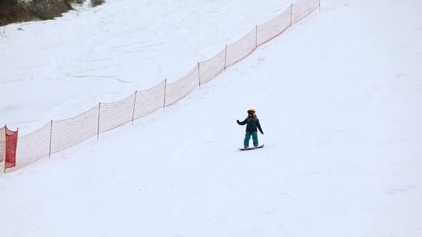 Maidan, Ucrania - 20 de febrero de 2021: niño aprendiendo a hacer snowboard — Vídeo de stock