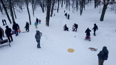 Kar parkındaki tepeden kayan mutlu aileler