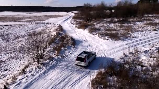 Повітряний вид на автомобіль, що рухається сніговим полем — стокове відео