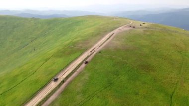 Hava manzaralı SUV aracı tepeden dağa doğru gidiyor.