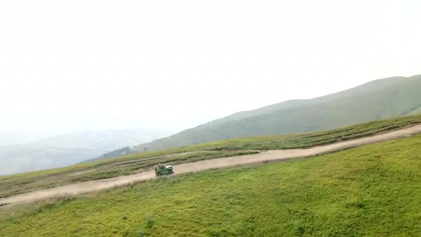 Veicolo di SUV di vista aerea che sale dalla collina alla cima della montagna — Video Stock