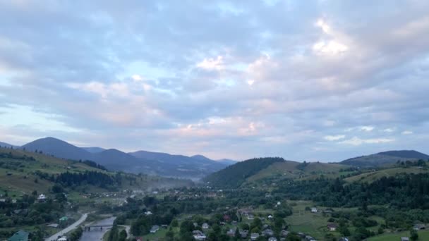 Vista aérea de las montañas de los Cárpatos con pequeño pueblo al atardecer — Vídeos de Stock