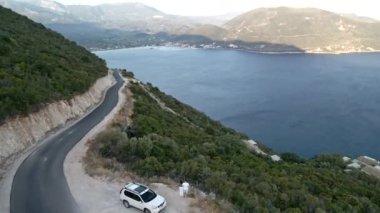 Araba yolculuğu konsepti. Soldaki adada deniz kenarındaki dağ yolunun havadan görünüşü.