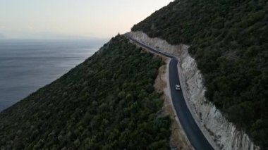 Araba yolculuğu konsepti. Soldaki adada deniz kenarındaki dağ yolunun havadan görünüşü.