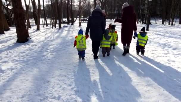 Lviv, Ukrayna - 10 Şubat 2021: yansıtıcı yelek giymiş bir grup çocukla kış parkında yürüyüş — Stok video