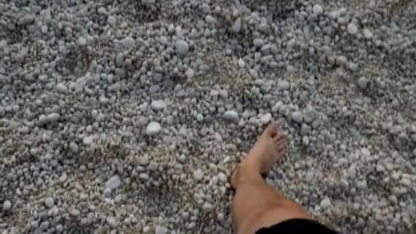 Точка зору чоловік ходить босоніж на скелястому морському пляжі — стокове відео
