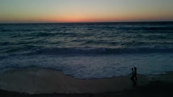 Coppia che guarda il tramonto sul mare con grandi onde — Video Stock
