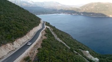 Araba yolculuğu konsepti. Soldaki adada deniz kenarındaki dağ yolunun havadan görünüşü.