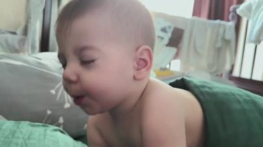 Huzurlu bebek yeşil bir battaniyenin üzerinde uyanıyor.