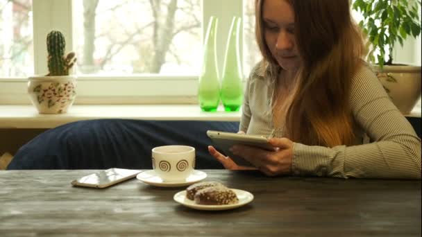 Fiatal lány használja tabletta olvasni, vagy valami mosolyogva ül — Stock videók