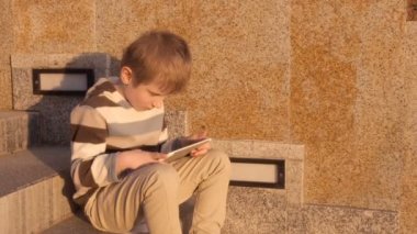 Mutlu genç çocuk parkta tablet bilgisayar kullanarak