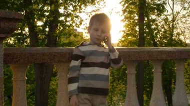 Cep telefonu üzerinde açık havada konuşurken genç gülümseyen çocuk