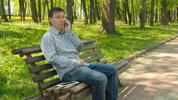Hombre de teléfono inteligente llamando en el teléfono móvil en el parque — Vídeos de Stock