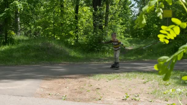 Bambino cavalca sui pattini a rotelle nel parco — Video Stock