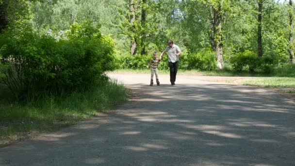 Fadern lär sin son att rida på rullskridskor — Stockvideo