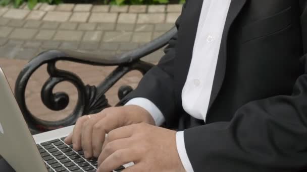 商人在笔记本电脑上键入并坐在街头长椅上 — 图库视频影像