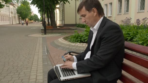 Businessman using his laptop to purchase something online with his credit card — Stock Video