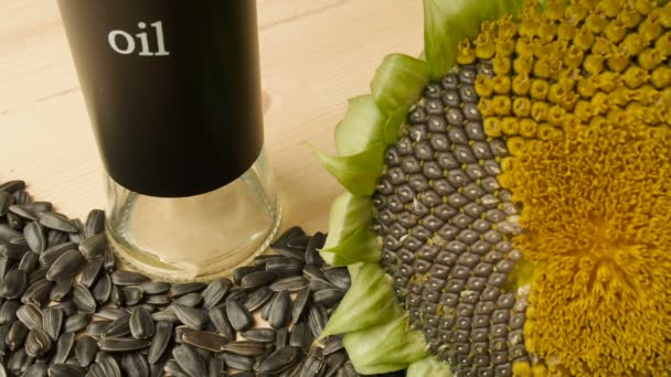 Slunečnicová semínka, slunečnicový květ na dřevěný stůl, slunečnicový olej se nalije do skleněné mísy, naklonění — Stock video