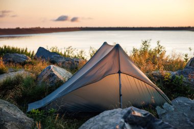 Güneş doğarken dağ yürüyüşü için dağ gölüne kamp kurun.