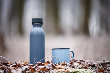 Termos ve seyahat kupası donmuş kış havasına sokulmuş. Sıcak içecek içecekleri.