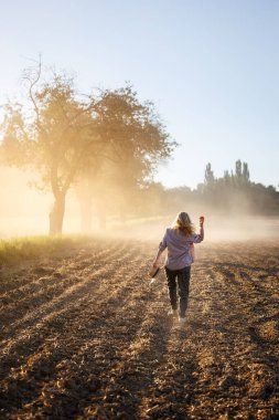 Çiftlikte kuraklık döneminde tozlu kuru tarlalarda yürüyen kadın çiftçi. İklim değişikliğinin tarım üzerindeki etkisi