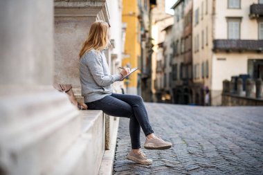 İtalya, Bergamo 'da eskiz defterine antik mimari çizen kadın. Avrupa 'da tatildeyken kadın ressam resim yapıyor.