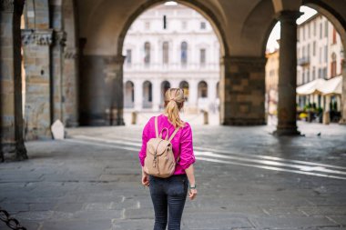 Piazza Duomo 'da kemer mimarisi altında duran ve İtalya' nın Bergamo şehrinde tatil yapan bir kadın. Tatil sırasında Avrupa 'yı keşfeden yalnız kadın turist