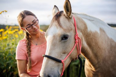 Hayvan çiftliğinde at destekli terapi. Gözlüklü beyaz kadın dışarıda terapi atlarını okşuyor.