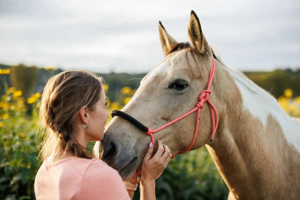 Kadın ve atı arasında sevgi dolu bir an. Boya atına yakın duran bir kadın çiftlik sahibi güven ve dostluğu ifade ediyor.