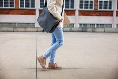 İş kadını elinde laptop çantasıyla şehir caddesinde yürüyor. Günlük iş kıyafetleri içinde bir kadın şirket binalarının önünde yürüyor.