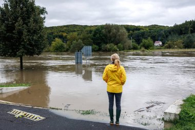 Nehir taşmış. Sel sırasında taşan suya bakan endişeli bir kadın. Aşırı hava ve doğal afet