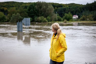 Nehir taşmış. Sel sırasında taşan suya bakan endişeli bir kadın. Aşırı hava ve doğal afet