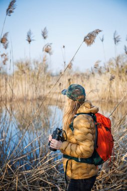 Kuşbilimci doğal ortamdaki kuş davranışlarını ortaya çıkardı. Göl kenarında dürbünlü su kuşları olan kadın.