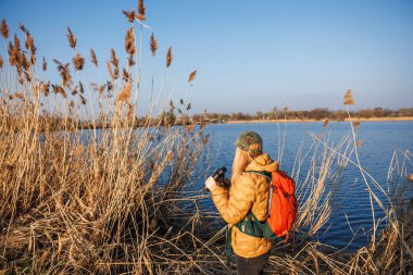 Kuş izleme. Dürbünlü bir kadın gölde vahşi hayvan ve kuş arıyor.